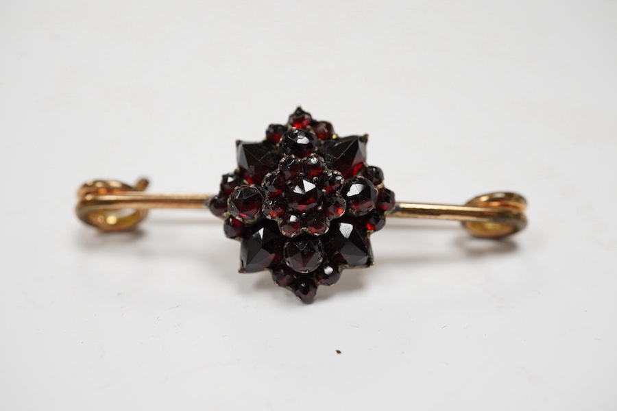 A rolled gold and garnet cluster set bar brooch, 44mm (adapted). Condition - poor to fair